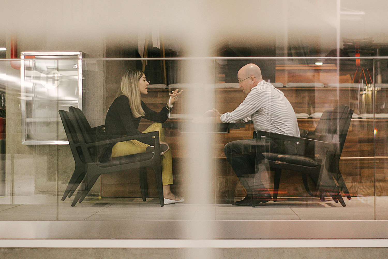 Image of 2 people in a business meeting through a glass window